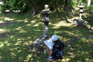 天神様の境内で石灯籠や背景の樹木を描く児童